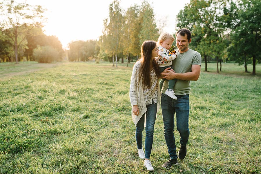 Photo of a happy family walking in a field with trees