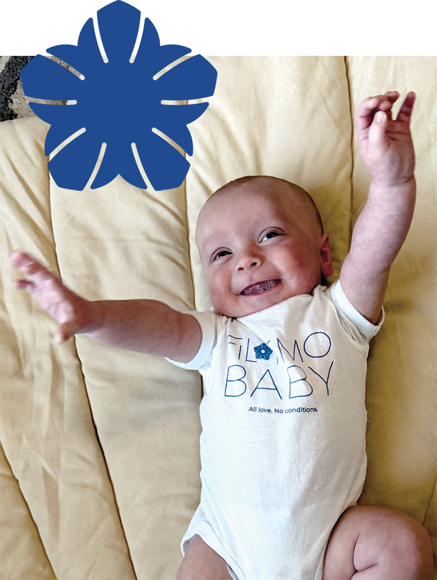 Photo of a happy baby with overlaying blue Filotimo flower