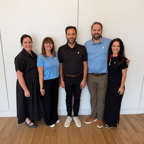 Filotimo leadership team standing together and smiling for a group photo against a white wall.