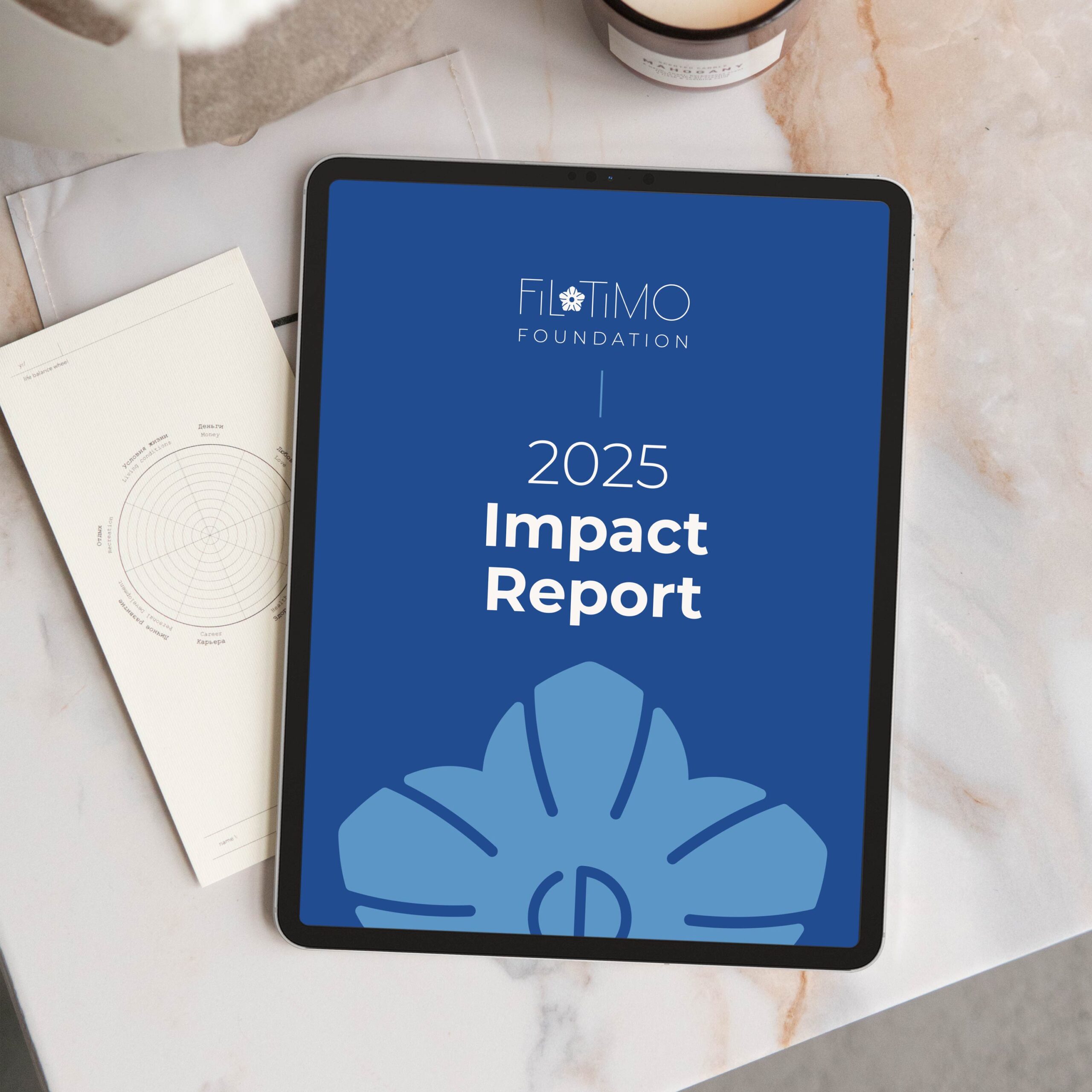 Filotimo Foundation’s 2025 Impact Report displayed on a tablet resting on a marble desk.